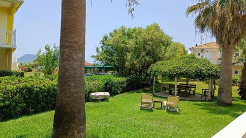 a yard with chairs and a table and a palm tree at Bonisis Studios in Laganas