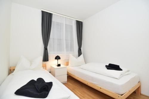 - une chambre avec 2 lits et une fenêtre dans l'établissement Flataid Apartments Stadion & Messe Graz, à Graz