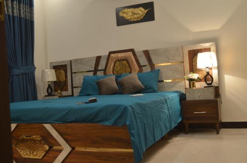 Schlafzimmer mit einem Bett mit blauer Bettwäsche und einem Spiegel in der Unterkunft Dream home 2 & 4 bedroom Family house in Karatschi