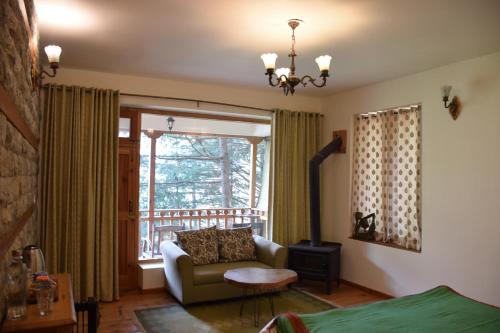 a living room with a couch and a window at Kudrat - A Boutique Homestay- Tirthan Valley in Banjār