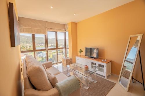 sala de estar con sofá y TV en Apartamentos Rurales de Abelleira, en Muros