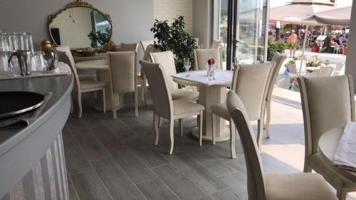 un restaurante con mesas y sillas blancas y un espejo en DIELL HOTEL, en Durrës