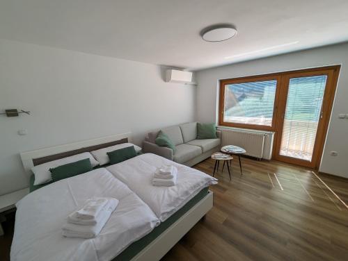 a white bedroom with a bed and a couch at Studio apartment Velis in Radovljica