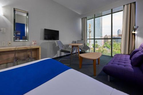 Habitación de hotel con cama y sofá púrpura en City Express Plus by Marriott Reforma El Ángel, en Ciudad de México