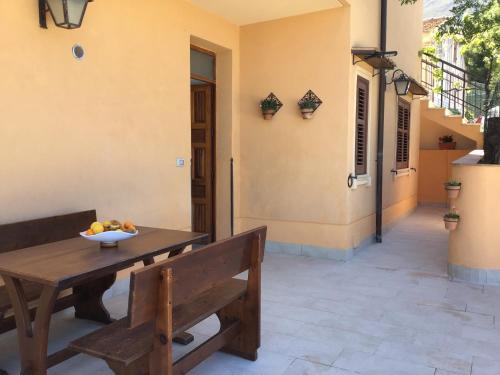 a table with a bowl of fruit and a bench at Casa LORE in Castelbuono