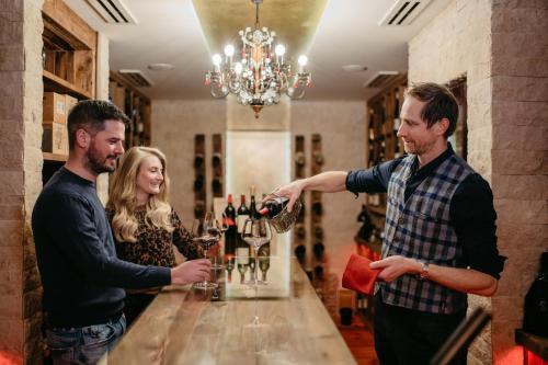 a man pouring a glass of wine at a bar at Hotel Salzburger Hof Zauchensee in Zauchensee
