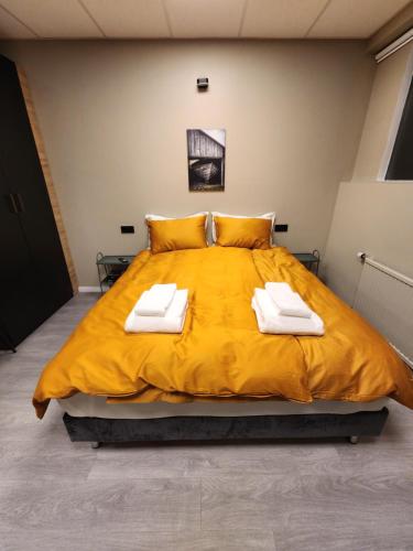 a bedroom with a large yellow bed with towels on it at Base apartments ap 210 - Capital region of Reykjavík in Hafnarfjördur
