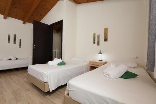 Habitación con 2 camas, paredes blancas y suelo de madera. en Georgioupolis polentas villa, en Georgioupolis