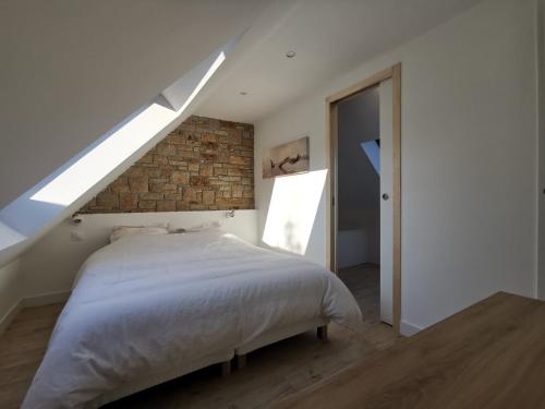 een slaapkamer met een bed en een bakstenen muur bij La terrasse in Fouesnant