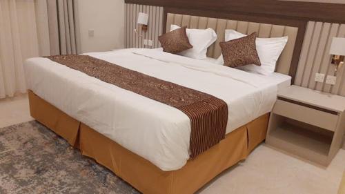 - un grand lit dans une chambre avec 2 tables dans l'établissement Nazik sweet - نازك سويت شقق فندقية, à Tabuk