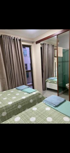 - une chambre avec 2 lits et un miroir dans l'établissement Alugo apartamento de luxo, 3 quartos, 2 vagas, à Cabo Frio