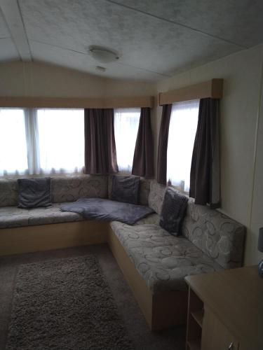 a living room with a couch in front of windows at Caravan for hire in Lancaster