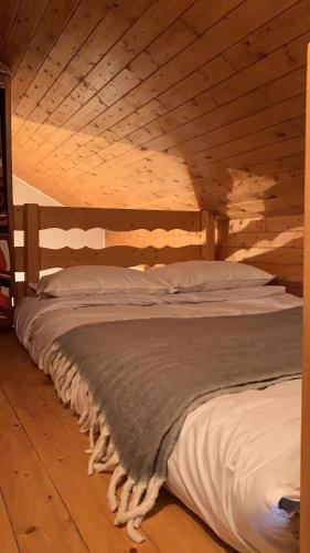 Cama en habitación con techo de madera en Appartement de montagne, en Bernex