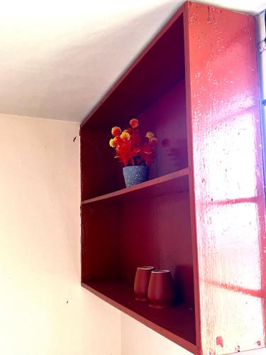 a red shelf with a vase with flowers in it at Acharya Compound in Udupi