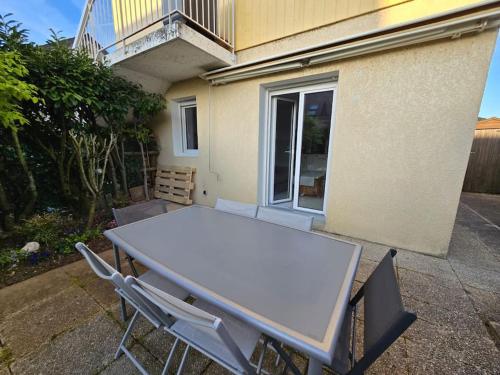 une table et des chaises blanches devant un bâtiment dans l'établissement La Violette, à Publier