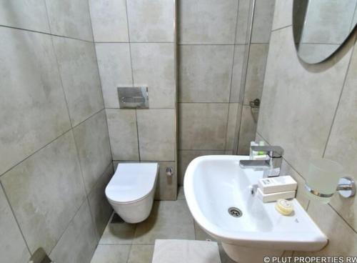 La salle de bains est pourvue de toilettes et d'un lavabo. dans l'établissement ACACUS ROYALE, à Kigali