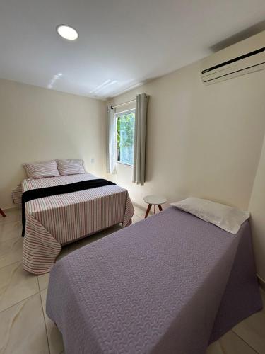 2 camas en una habitación con ventana en Apart Recanto da Floresta, en Salvador