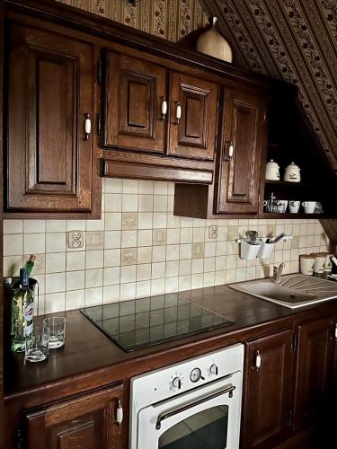 a kitchen with wooden cabinets and a white oven at DOM GOŚCINNY NAD JEZIOREM BIAŁYM in Gorzewo