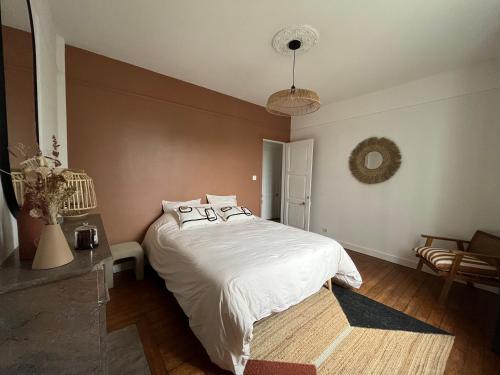 une chambre avec un lit avec des draps blancs et des oreillers dans l'établissement Le Cottage Clecy, à Clécy