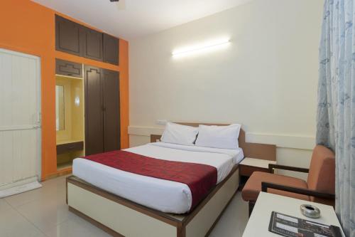 a bedroom with a bed and a desk and a chair at Hotel Telehaus International in Bangalore