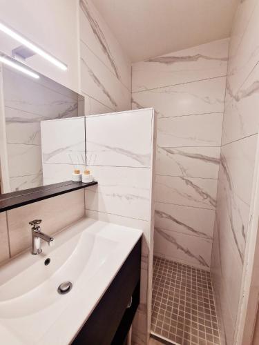 une salle de bain blanche avec un lavabo et un miroir dans l'établissement appartement cosy en centre ville avec terrasse, à Villefranche-sur-Saône