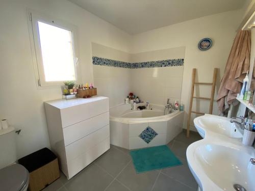 une salle de bain blanche avec une baignoire et un lavabo dans l'établissement Maison avec piscine donnant sur les vignes, proche d'Uzes, à Valliguières