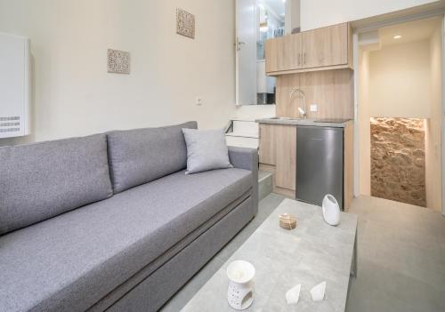 a living room with a gray couch and a kitchen at Avgoustinos house in Chios