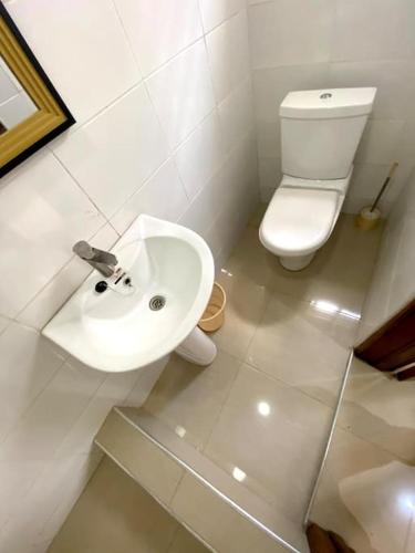 a white bathroom with a toilet and a sink at Spacious 2 Bedroom House East Legon Accra in Accra
