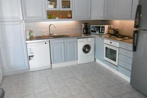 une cuisine avec des armoires blanches et une machine à laver dans l'établissement 120m2-3 chambres parking et piscine à La Ciotat, à La Ciotat
