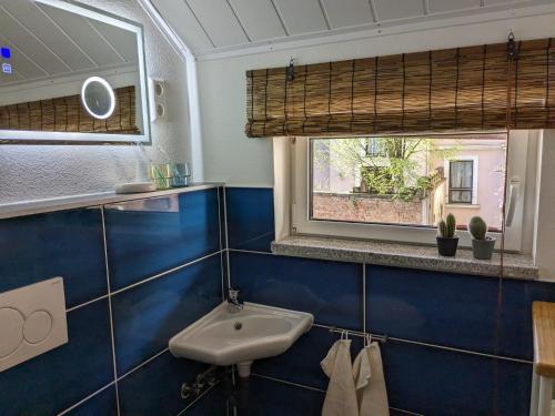 a blue tiled bathroom with a sink and a window at Altes Häusle am Waschbach Anno 1625 Ferienwohnungen und Doppelzimmer in Edenkoben