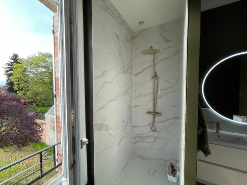 La salle de bains est pourvue d'une douche avec un miroir et un lavabo. dans l'établissement Maison Coeur centre ville Arnage 24h du Mans, à Arnage