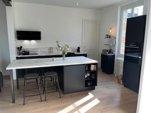 une cuisine avec un grand îlot et deux tabourets de bar dans l'établissement Maison Coeur centre ville Arnage 24h du Mans, à Arnage