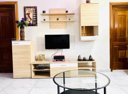 a living room with a glass table and a television at Ferrez Apartment in Accra