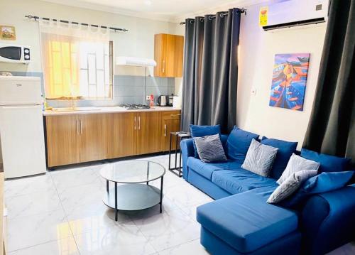 a living room with a blue couch and a kitchen at Ferrez Apartment in Accra
