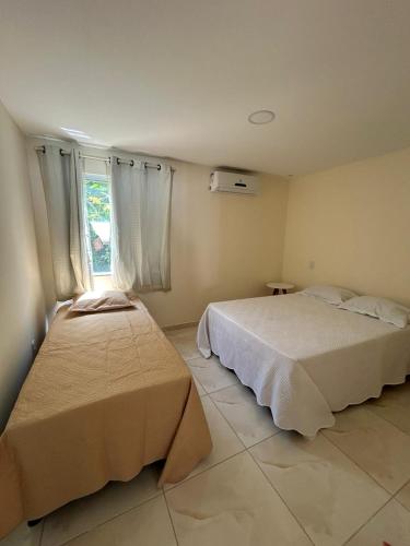 1 dormitorio con 2 camas y ventana en Apart Recanto da Floresta en Camaçari