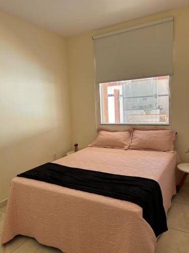 um quarto com uma cama grande e uma janela em Apart Recanto da Floresta em Camaçari