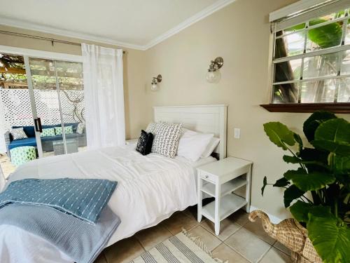 a bedroom with a white bed and a plant at Beachside Historic Cottage - Steps to Sand! in Clearwater Beach