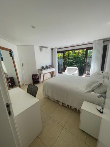 a white bedroom with a bed and a window at Casa Villa Lele in Salvador
