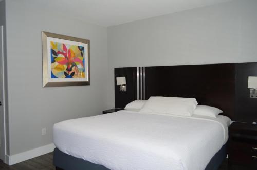 a white bed in a bedroom with a painting on the wall at Fairview Inn & Suites in Healdsburg