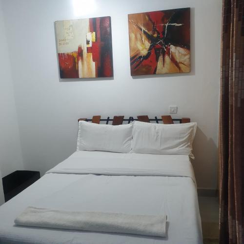1 dormitorio con 1 cama blanca y 3 cuadros en la pared en Racecourse one bed apartment ngong Road, en Nairobi