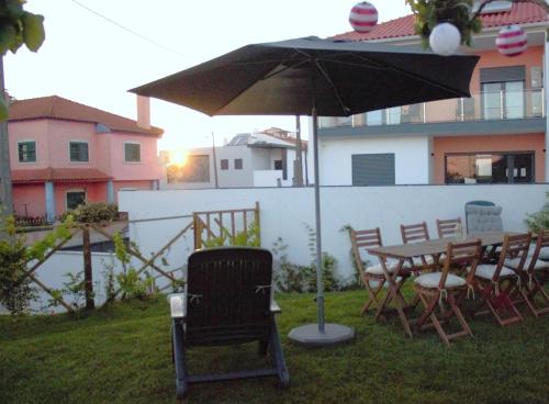 a table and chairs under an umbrella in a yard at Relax & Travel in Almada