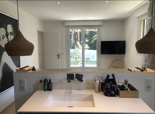 une salle de bain avec un lavabo et un grand miroir dans l'établissement Charmant appartement avec jardin à 10 mn du Palais, à Cannes