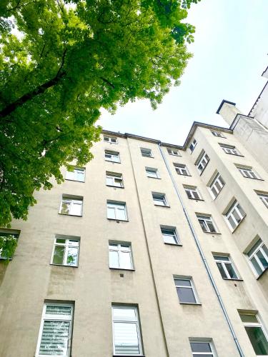 a tall building with many windows and a tree at Olivia Apartments - Słoneczny apartament w centrum Warszawy, Plac Unii Lubelskiej, Łazienki Królewskie, Pole Mokotowskie - 24h check-in in Warsaw