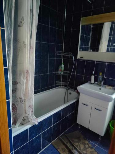 La salle de bains est pourvue de carrelage bleu, d'une baignoire et d'un lavabo. dans l'établissement Kwatery -pokoje pracownicze, tanie noclegi, à Białogard