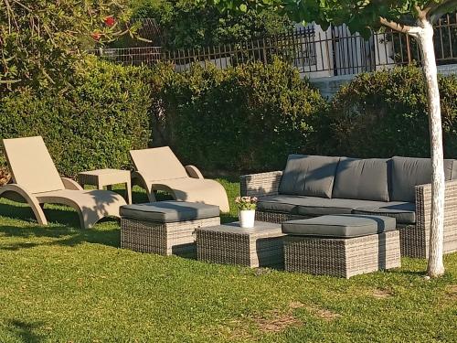 a group of wicker chairs and a couch in a yard at A&V's Home in Áyioi Apóstoloi