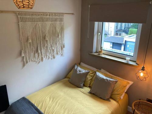 a bedroom with a bed with pillows and a window at Rustic Top Floor West End Pad With Balcony, Parking next to Byers Road, Aston Lane, Glasgow Uni in Glasgow