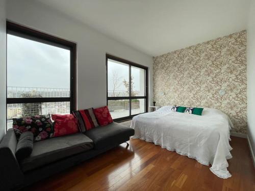 - une chambre avec un lit, un canapé et des fenêtres dans l'établissement Duplex de 160 m2 vue sur Seine, à Boulogne-Billancourt
