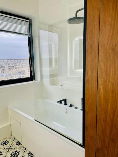 La salle de bains blanche est pourvue d'une baignoire et d'une fenêtre. dans l'établissement Duplex de 160 m2 vue sur Seine, à Boulogne-Billancourt