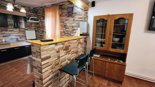uma cozinha com uma parede de tijolos e um bar com bancos em La Izvor Lepsa em Lepsa