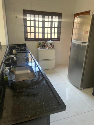 eine Küche mit einer Spüle und einem Kühlschrank in der Unterkunft Casa de praia Itanhaém Cibratel 2 concorrida in Itanhaém